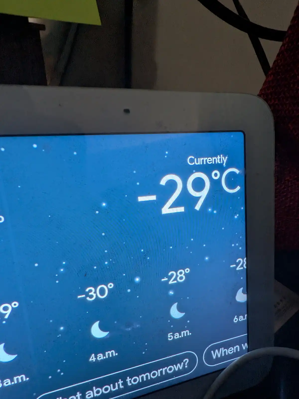 A close-up of a tablet displaying a weather app with a current temperature of -29°C, and a forecast showing temperatures…