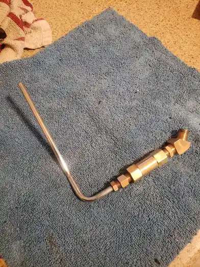 A homemade pipe wrench, constructed from a bent metal rod and brass fittings, rests on a blue microfiber towel. The overlaid…