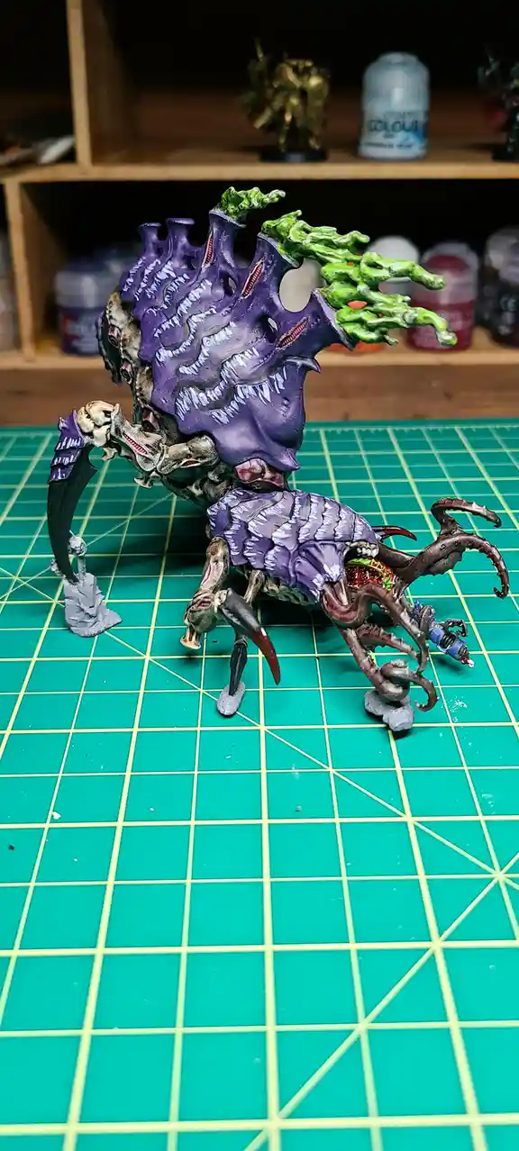 A highly detailed, painted miniature of a grotesque, multi-limbed creature with a large purple, fleshy mass on its back and…