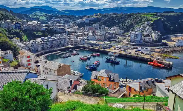 A scenic, high-angle photograph of a picturesque coastal town nestled in a bay, with colorful buildings climbing hillsides…
