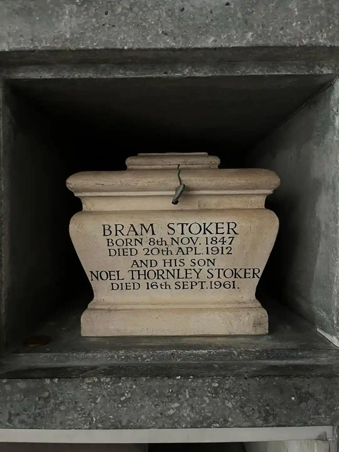 A stone tombstone inside a concrete niche displays engraved text identifying Bram Stoker and his son Noel Thornley Stoker…