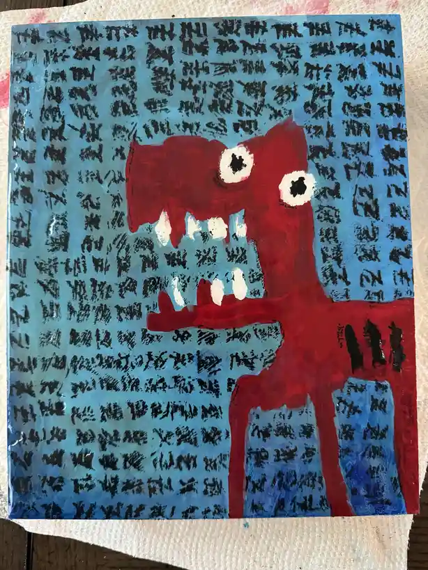 A childlike painting depicts a red, bipedal monster with large white eyes, black pupils, and sharp white teeth against a…