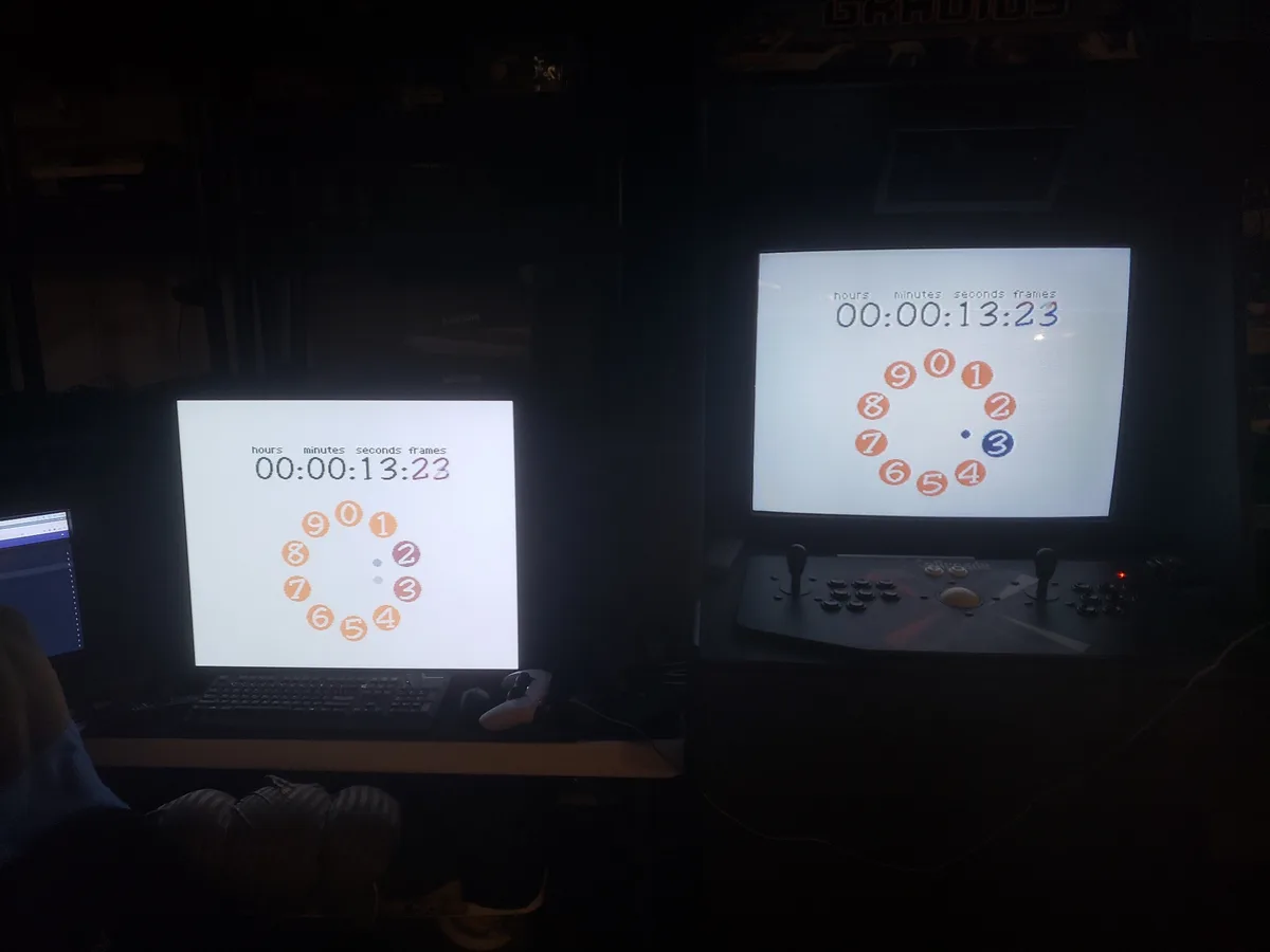 Two computer monitors in a dark room display the same digital timer reading 00:00:13:23, each with a circular number pad…