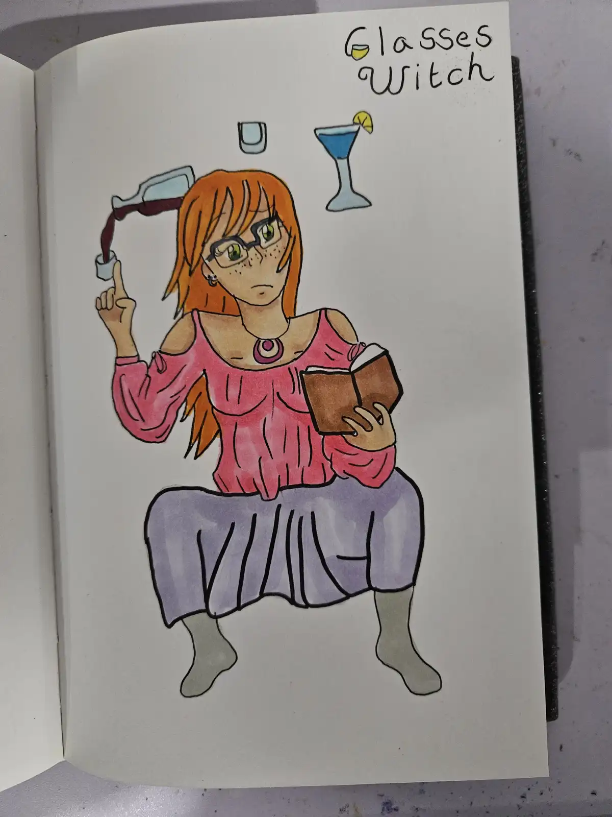 A hand-drawn illustration in a sketchbook shows a woman with orange hair and glasses, wearing a pink top and purple skirt…