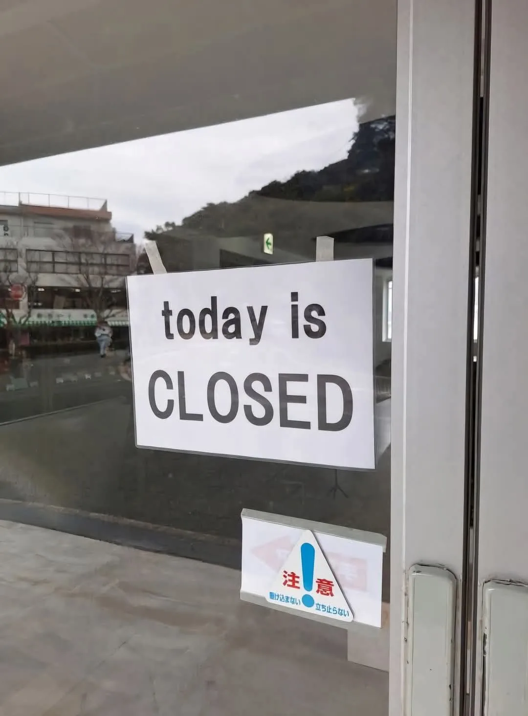 A white sign taped to a glass door reads 'today is CLOSED' in bold black text. Below it, a smaller Japanese warning sign…