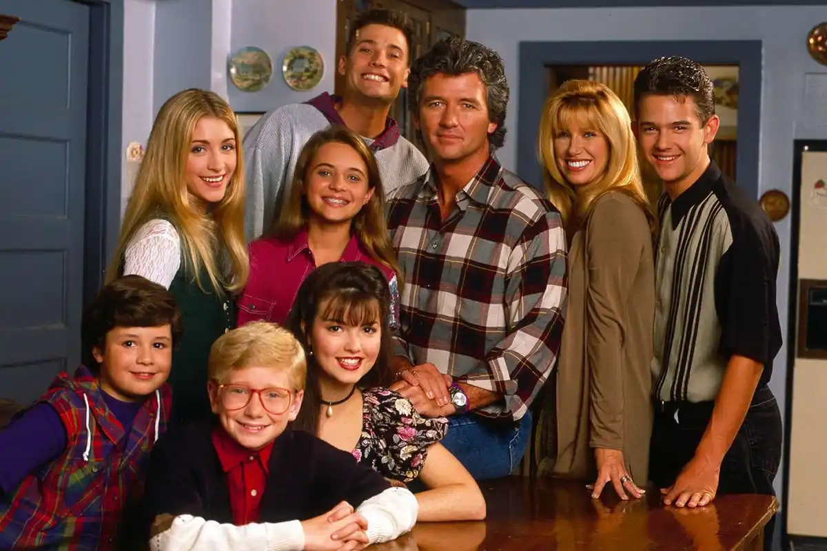 A promotional photo of the cast of the 1990s TV show 'Full House' poses together in a kitchen. The overlaid text reads 'i'm…