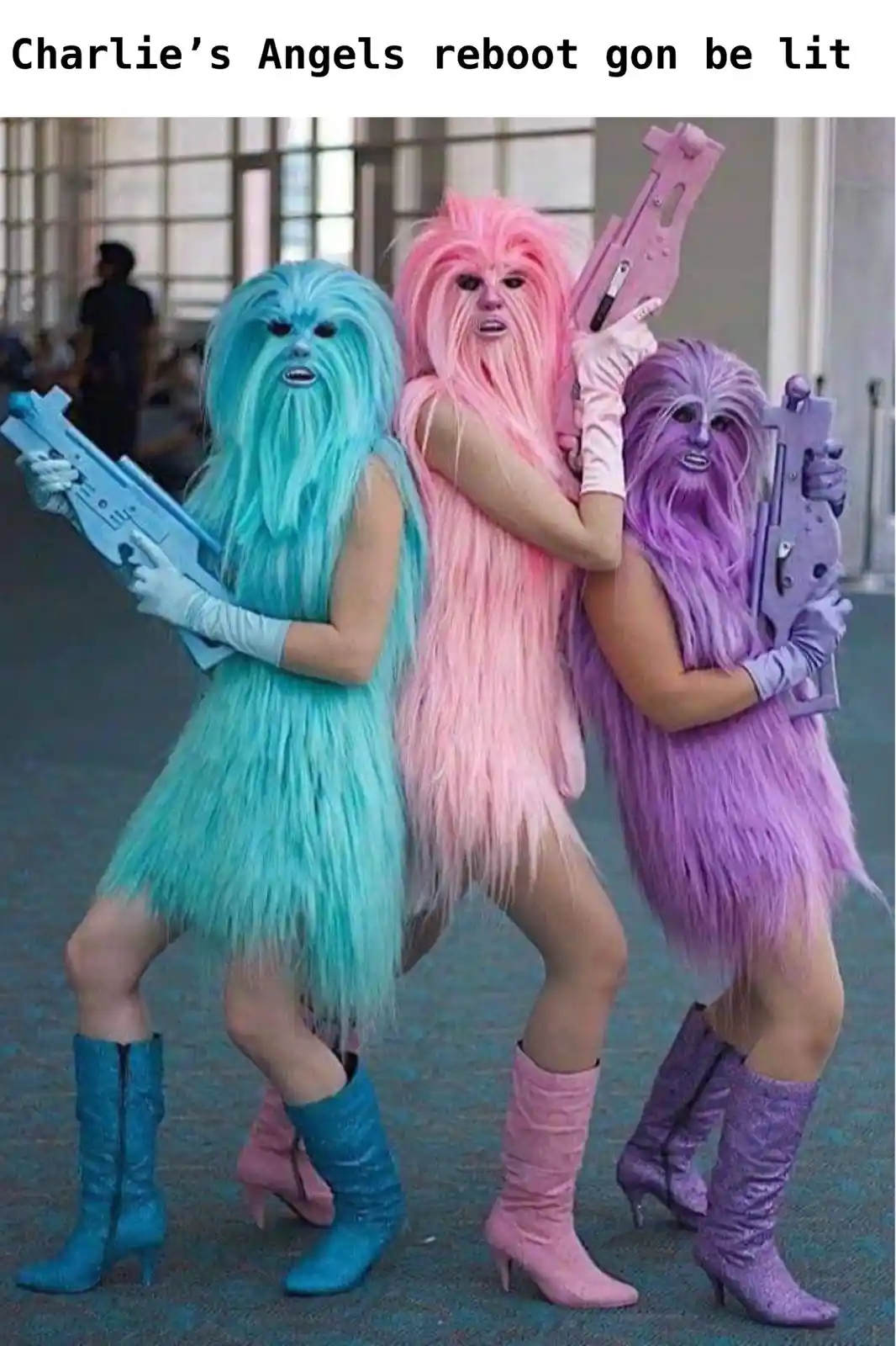 Three people dressed as colorful, furry Wookiee-like characters in blue, pink, and purple, each holding a matching toy…