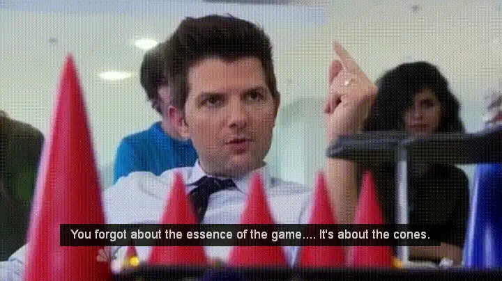 A still from the TV show 'The Office' featuring a man in a white shirt and tie, sitting in a conference room with red and…