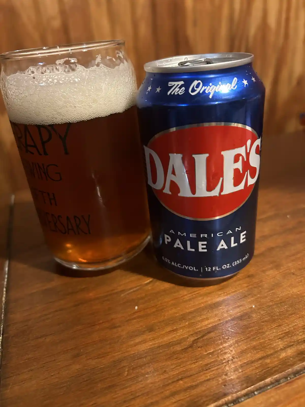 A can of Dale's American Pale Ale sits next to a glass filled with beer and topped with foam, both resting on a wooden…