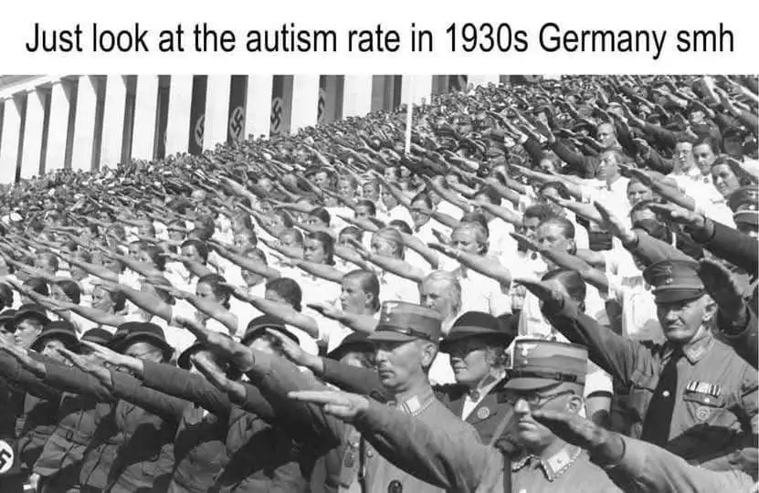 A black-and-white historical photograph shows a massive crowd of people, including men, women, and children, performing the…