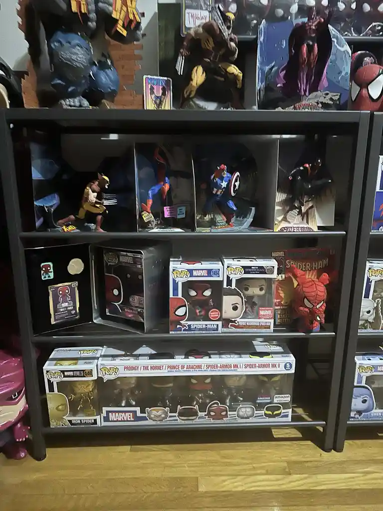 A black shelving unit displays a large collection of Marvel merchandise, including Funko Pop! figures in boxes, larger…