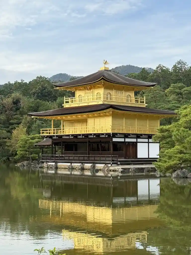 A serene photograph of the Kinkaku-ji (Golden Pavilion) in Kyoto, Japan, a two-story wooden structure with gold leaf…