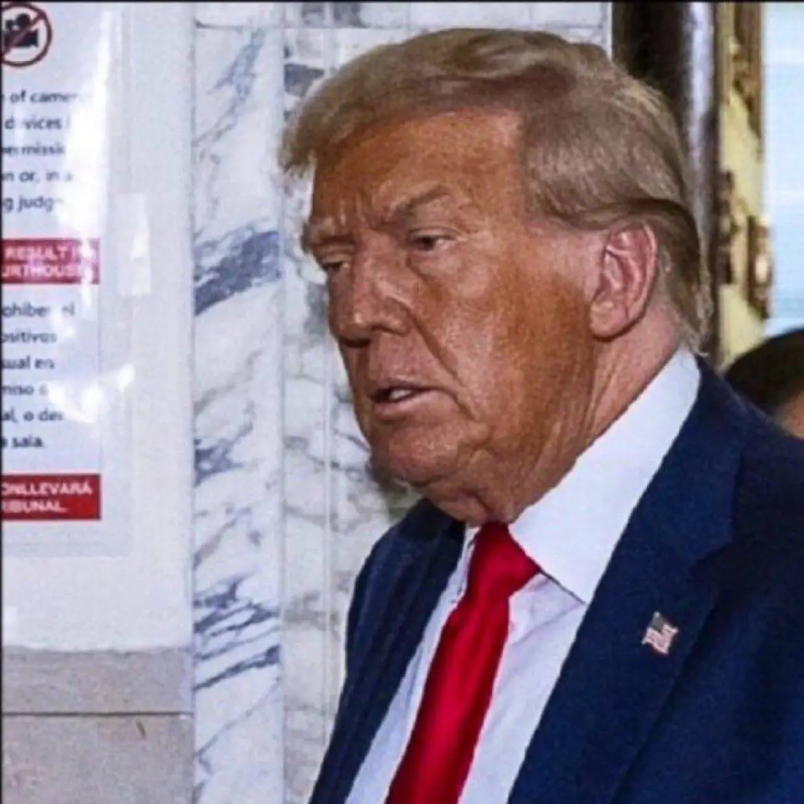 A close-up photo of Donald Trump looking slightly to his left with a serious expression, wearing a dark blue suit, white…