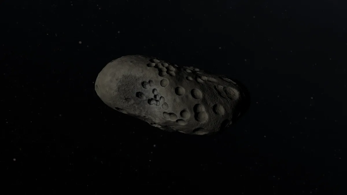 A gray, irregularly shaped asteroid with numerous craters floats against a starry black background. The overlaid text reads…