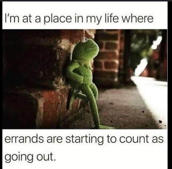 A green puppet resembling Kermit the Frog is shown leaning against a brick wall in a dimly lit outdoor setting, appearing…
