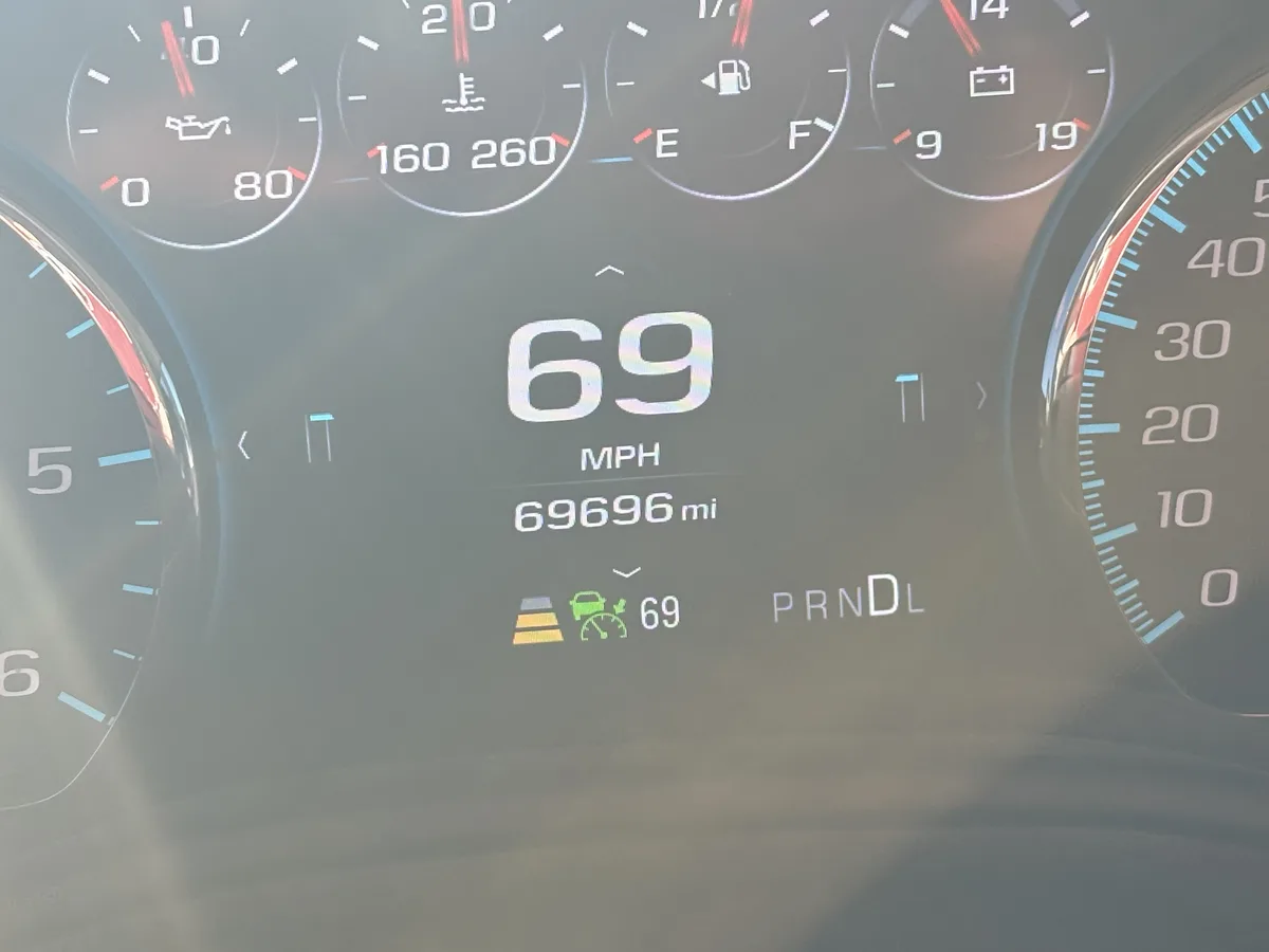A close-up of a car's digital dashboard showing the speed at 69 mph and the odometer reading 69696 miles, with the numbers…