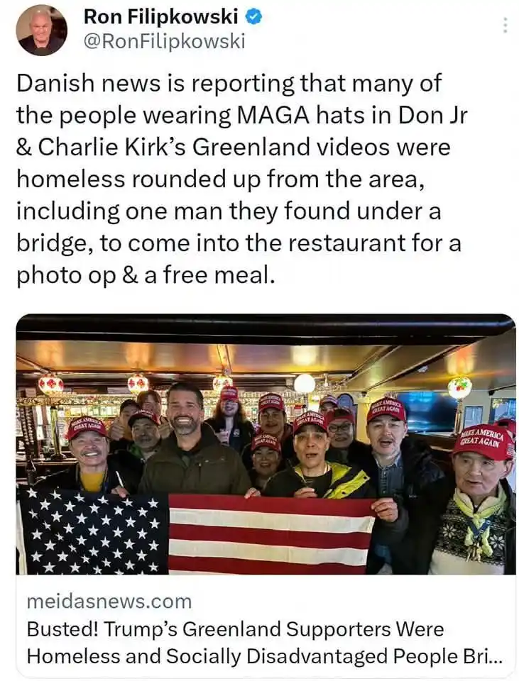A group of people wearing red 'Make America Great Again' hats are posing together indoors, holding an American flag. The…