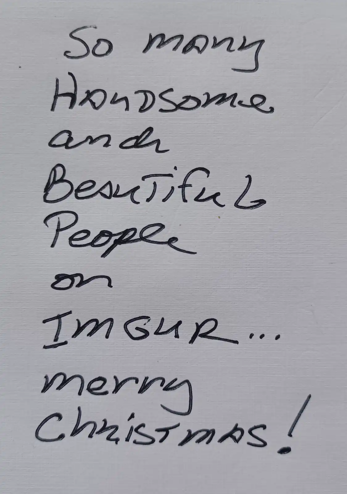 A close-up of handwritten text in black ink on textured white paper. The text reads 'So many Handsome and Beautiful People…