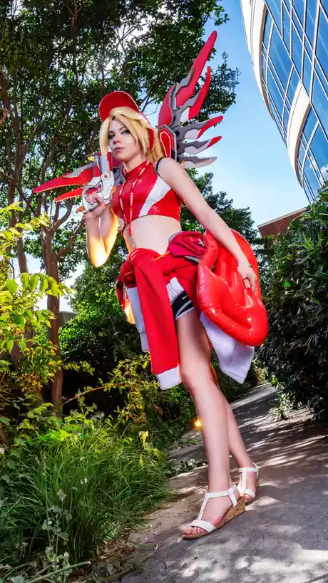 A cosplayer dressed as the video game character Ashe from Overwatch, holding her weapon and wearing her signature red and…