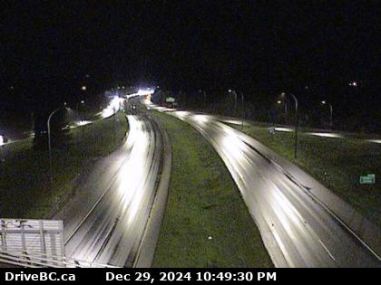 A nighttime highway camera feed shows a mostly empty multi-lane road with streaks of light from moving vehicles, captured by…