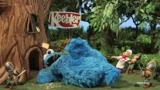 A large blue furry Cookie Monster lies on the ground in front of a treehouse with a 'Keebler' sign, while several small…