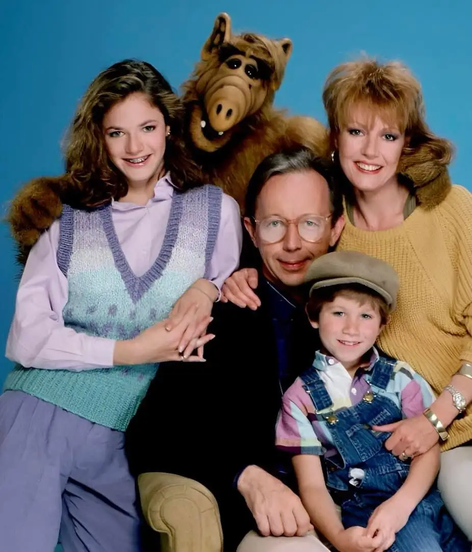 A family photo from the 1980s TV show 'ALF' featuring the main cast: a woman with braces, a man with glasses, a young boy in…