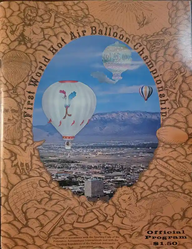 The image shows the cover of an official program for the 'First World Hot Air Balloon Championship,' featuring a central…