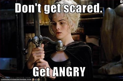 A woman with blonde hair, wearing a black outfit and holding a sword with a skull handle, stares intently. White bold text…