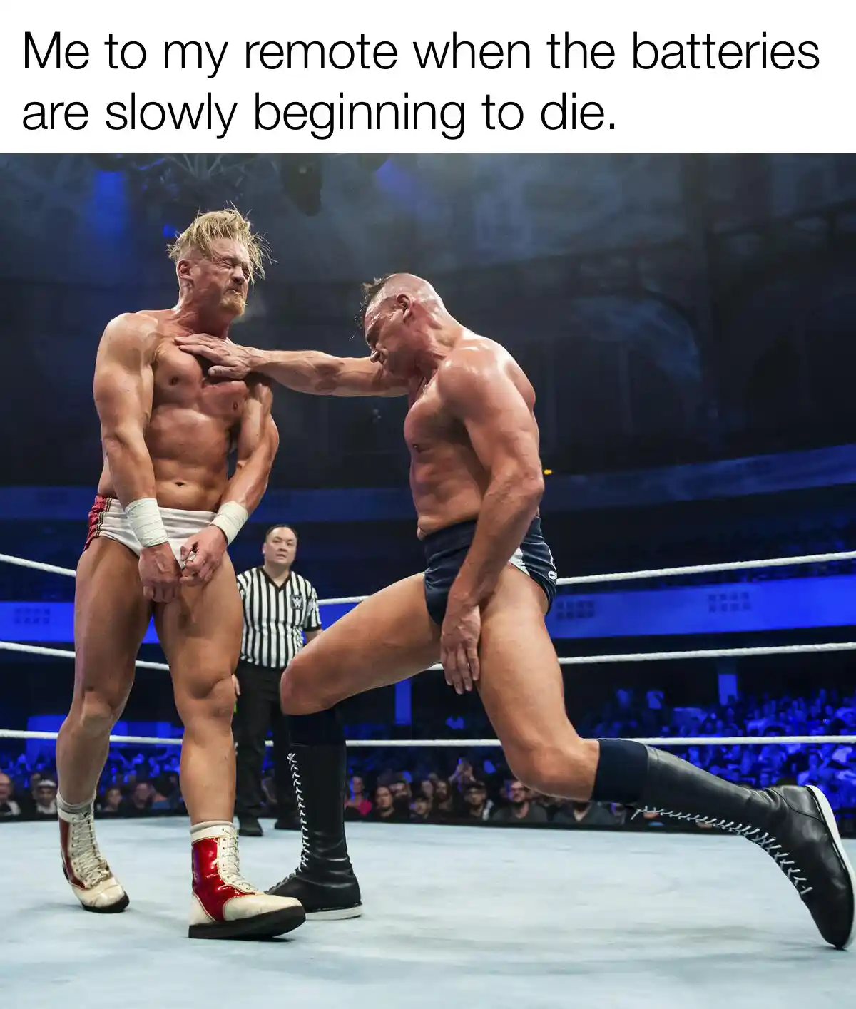Two muscular wrestlers are in a ring, one is delivering a powerful blow to the other's chest while the referee watches. The…