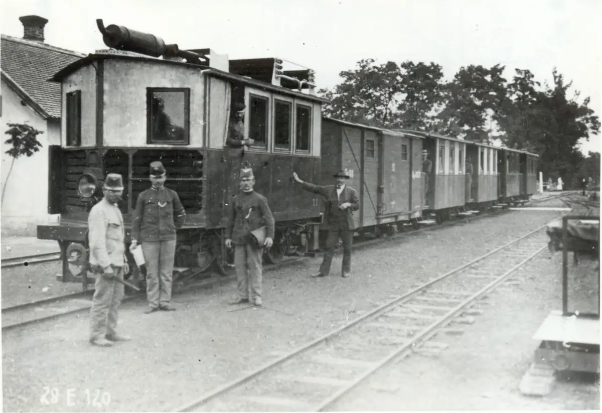 A vintage black-and-white photograph shows a long train with several men standing beside it on a railway track. One man in a…