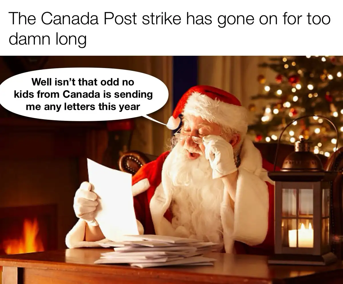 Santa Claus sits at his desk in a warmly lit room with a fireplace and a lit lantern, holding a blank letter and looking…