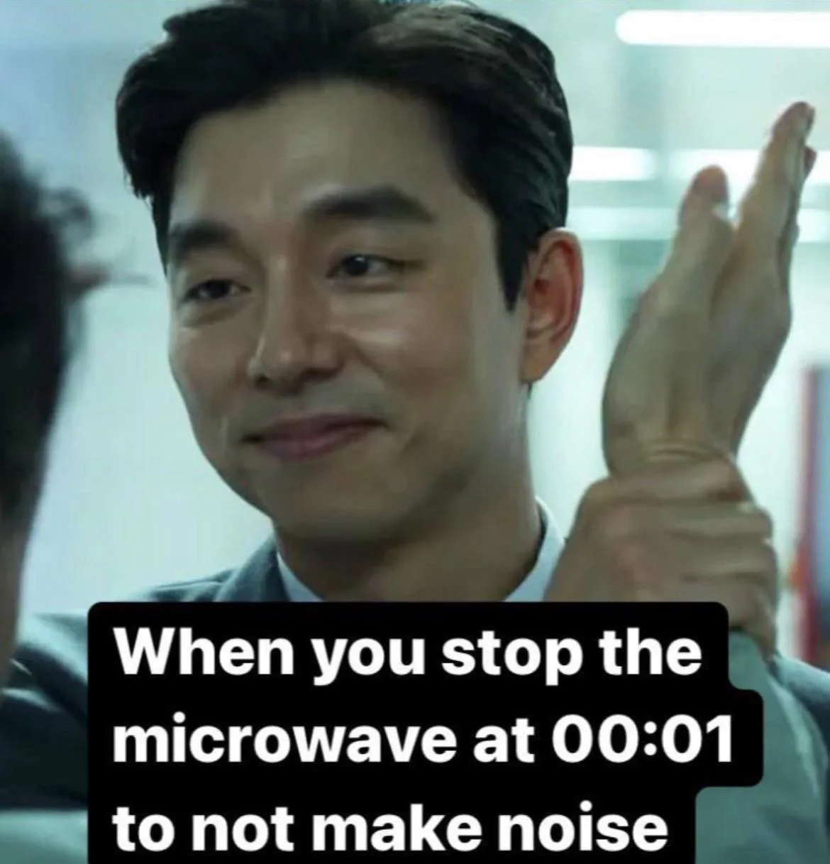 A man in a suit smiles smugly while holding up his hand, overlaid with text describing the act of stopping a microwave at…