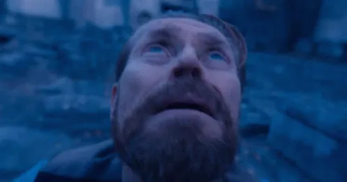 The image shows a man with a beard and blue eyes looking upward with a shocked or horrified expression, captured in six…