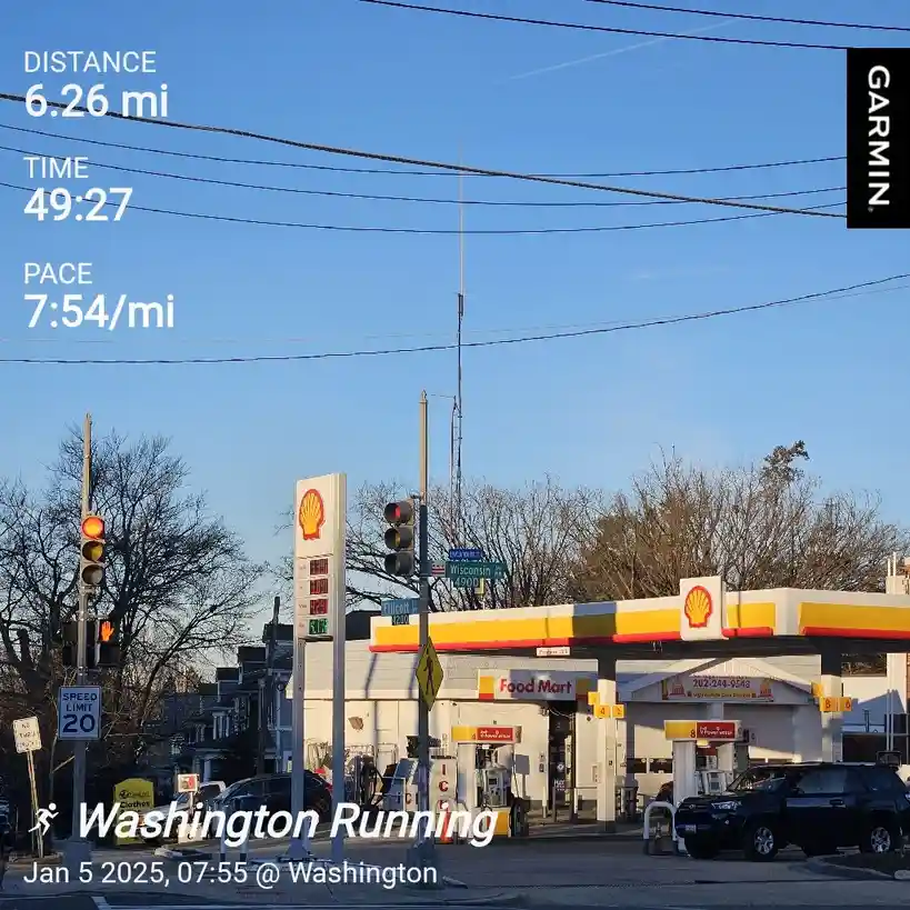 A Garmin running app screenshot overlays a photo of a Shell gas station with a red traffic light. The stats show a 6.26-mile…