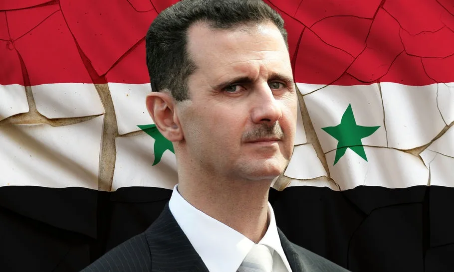 a man in a suit and tie stands in front of a cracked and broken syrian flag, which has red, white, and black stripes with…