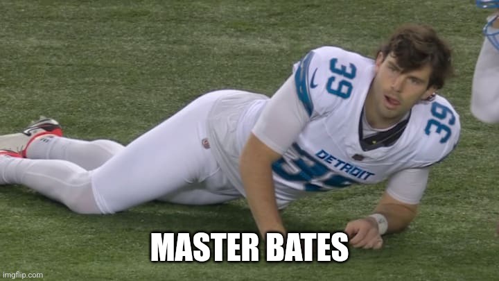 A football player in a white Detroit Lions uniform with number 39 is lying on his side on the grass, looking up with a…