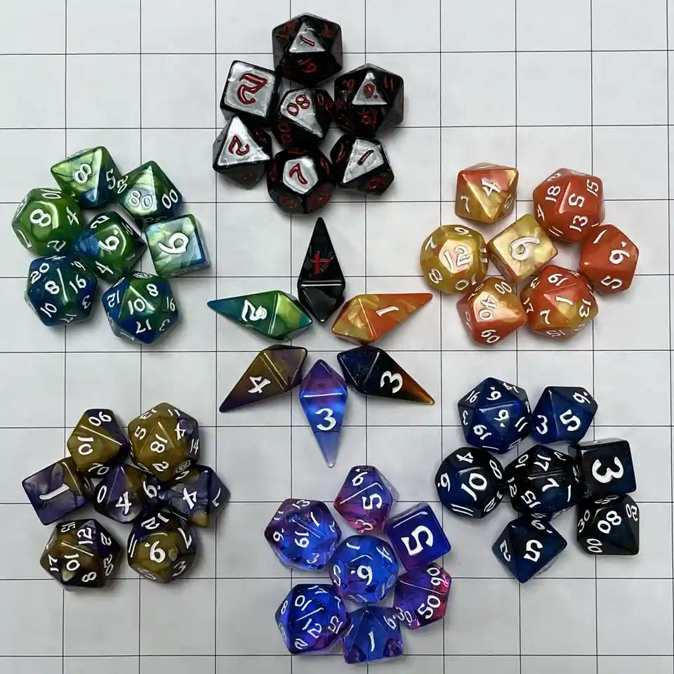 An overhead shot displays multiple colorful, translucent polyhedral dice arranged in five clusters on a white gridded…