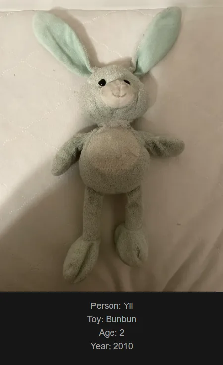 A light gray plush bunny toy with light green ears lies on a white quilted surface. Text overlaid at the bottom identifies…