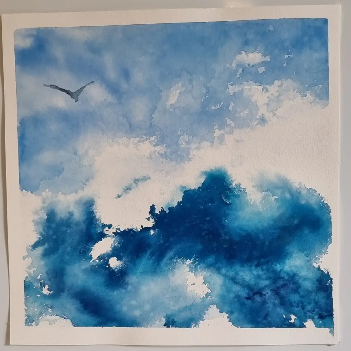 A watercolor painting depicts a sky with blue and white clouds, a single bird flying in the upper left, and a large dark…