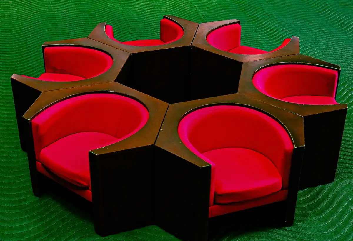 The image displays a six-seater modular seating arrangement with bright red cushions and dark wood frames, set against a…