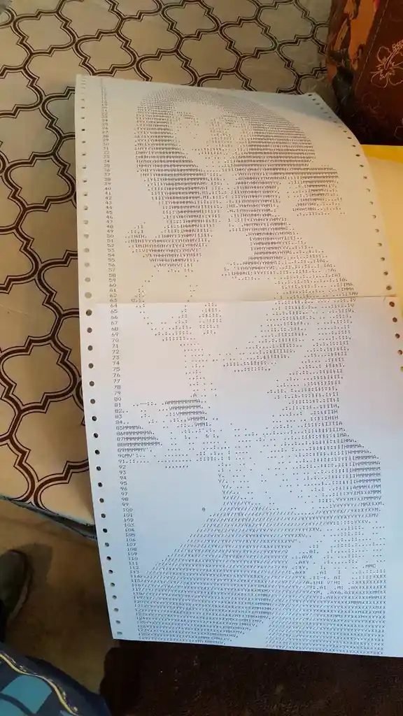 A close-up photo shows a long, multi-page document filled with dense, illegible text, likely a printout of a computer…