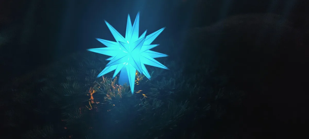 A glowing blue, multi-pointed star-shaped ornament sits atop a dark, pine-like tree, with faint orange lights visible below…