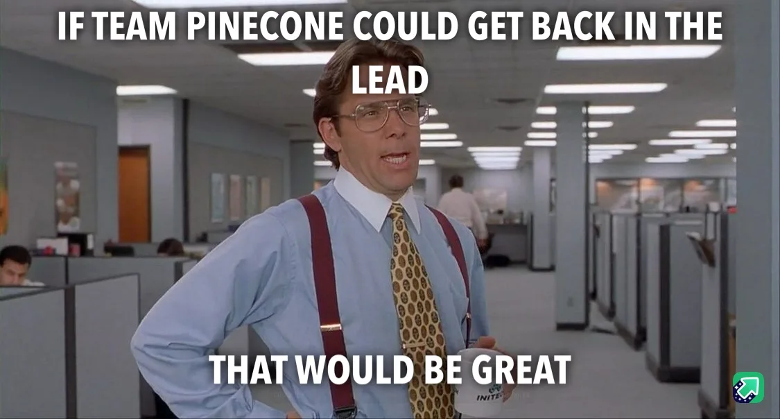 A man in a light blue shirt, patterned tie, and red suspenders stands in an office hallway with cubicles, holding a mug. He…