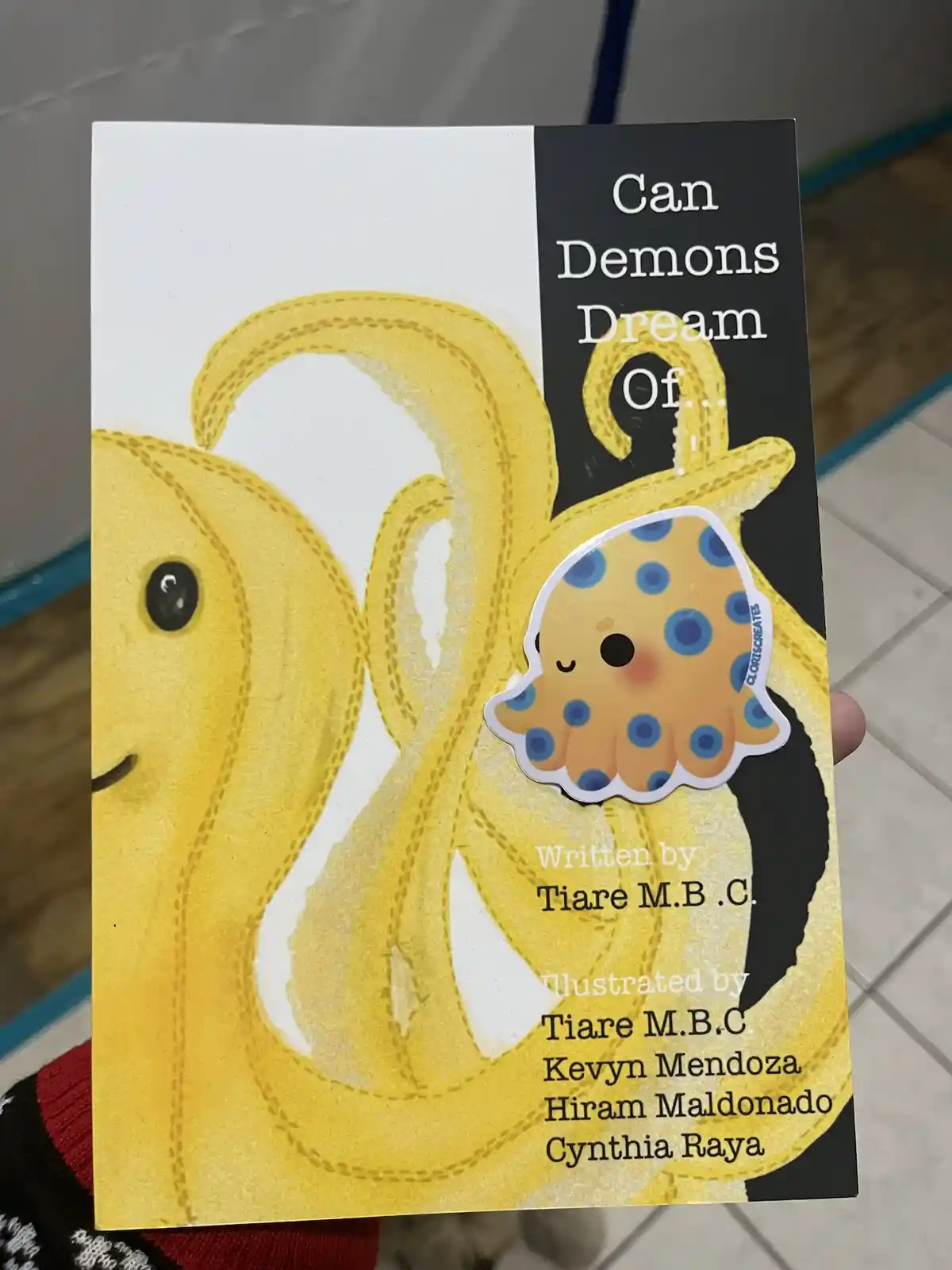 A book cover titled 'Can Demons Dream Of...' features a large, friendly-looking yellow octopus illustration. A small, cute…