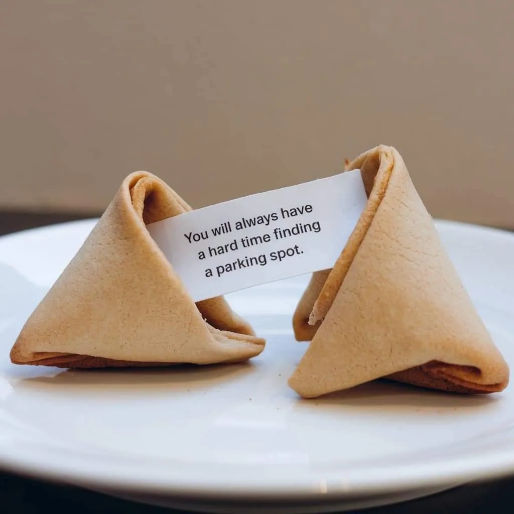 A fortune cookie, split open on a white plate, reveals a paper slip with the text 'You will always have a hard time finding…