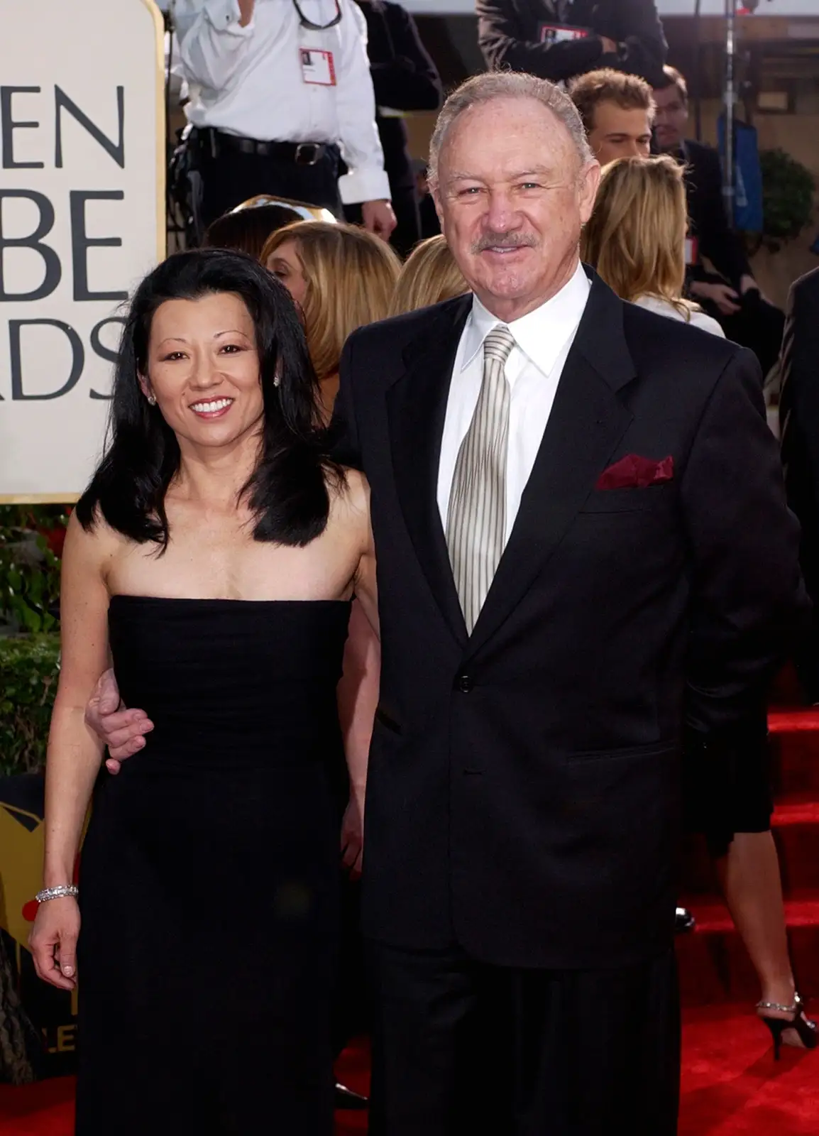 A man and woman pose together on a red carpet at the Golden Globe Awards, with the man's arm around the woman. The man is…