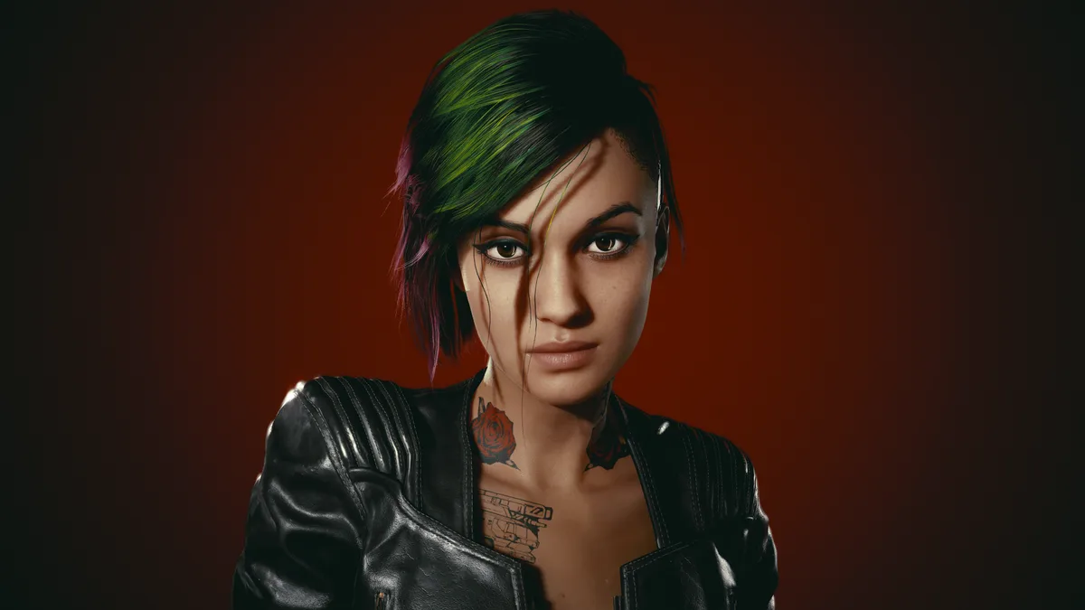 A woman with short, dark hair streaked with green and purple, wearing a black leather jacket, stares intensely at the…