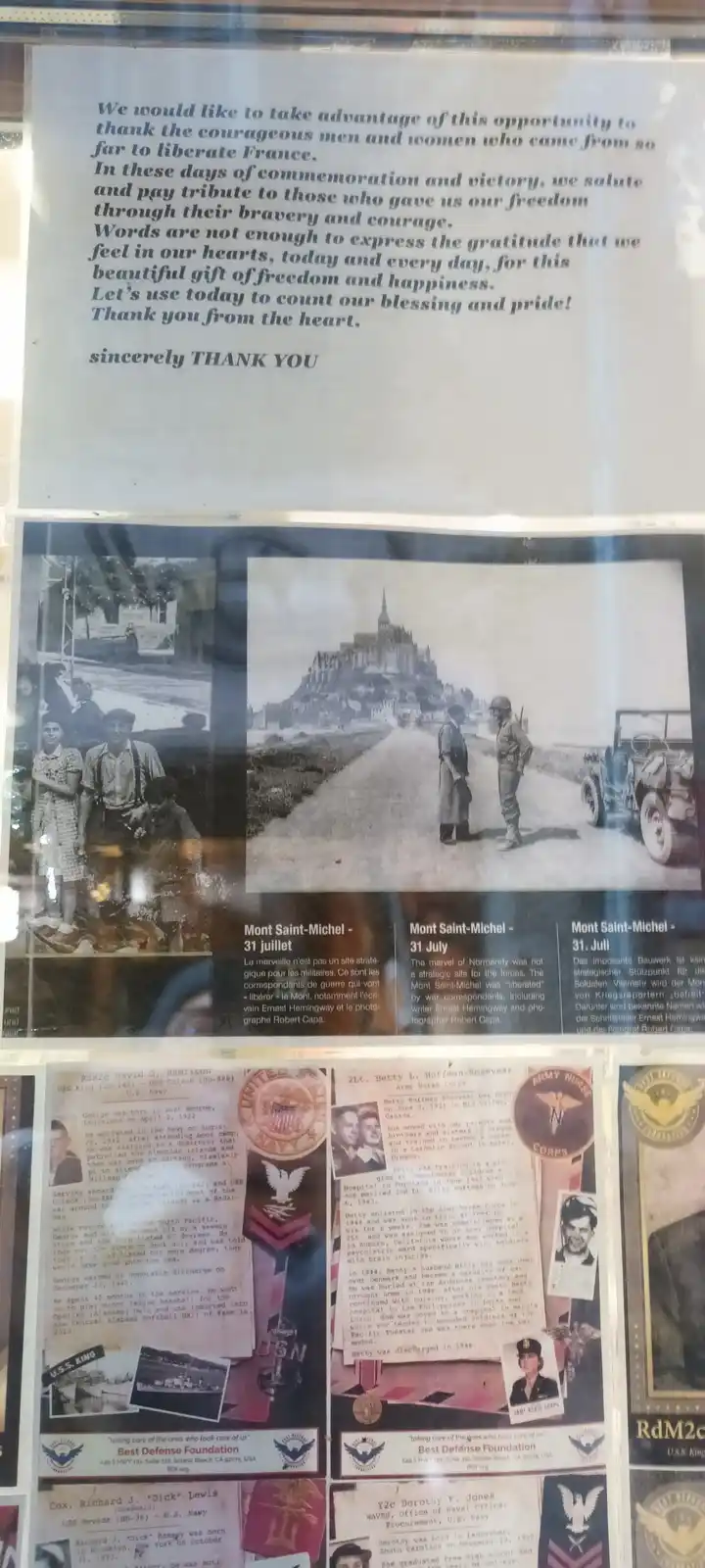 A museum display panel featuring historical photos and text about WWII, including a photo of soldiers at Mont Saint-Michel…