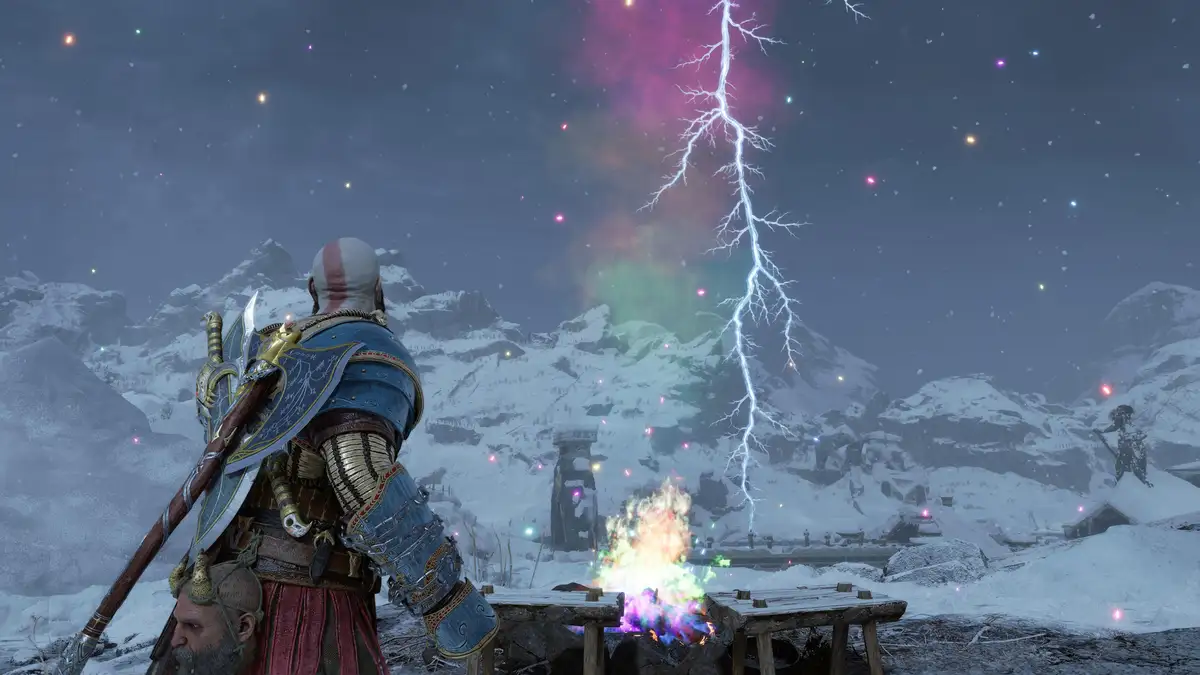 A bald warrior in ornate blue and gold armor stands in a snowy mountain landscape, looking at a campfire and a massive…