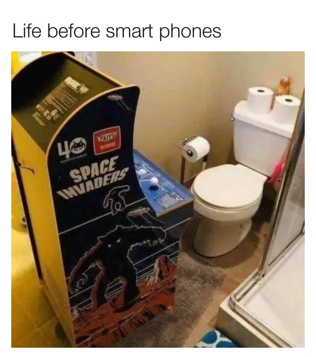 A bathroom scene featuring a vintage 'Space Invaders' arcade machine placed next to a toilet and shower, with toilet paper…